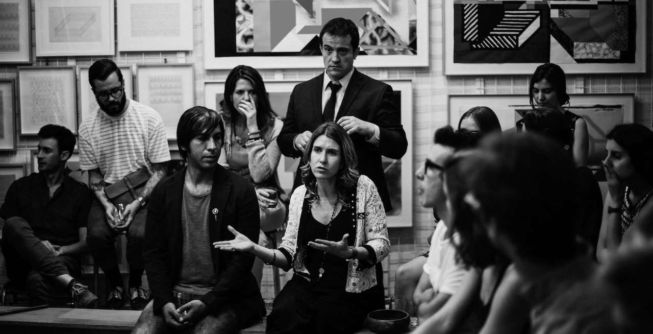 People seated in a room listening to a woman have her say